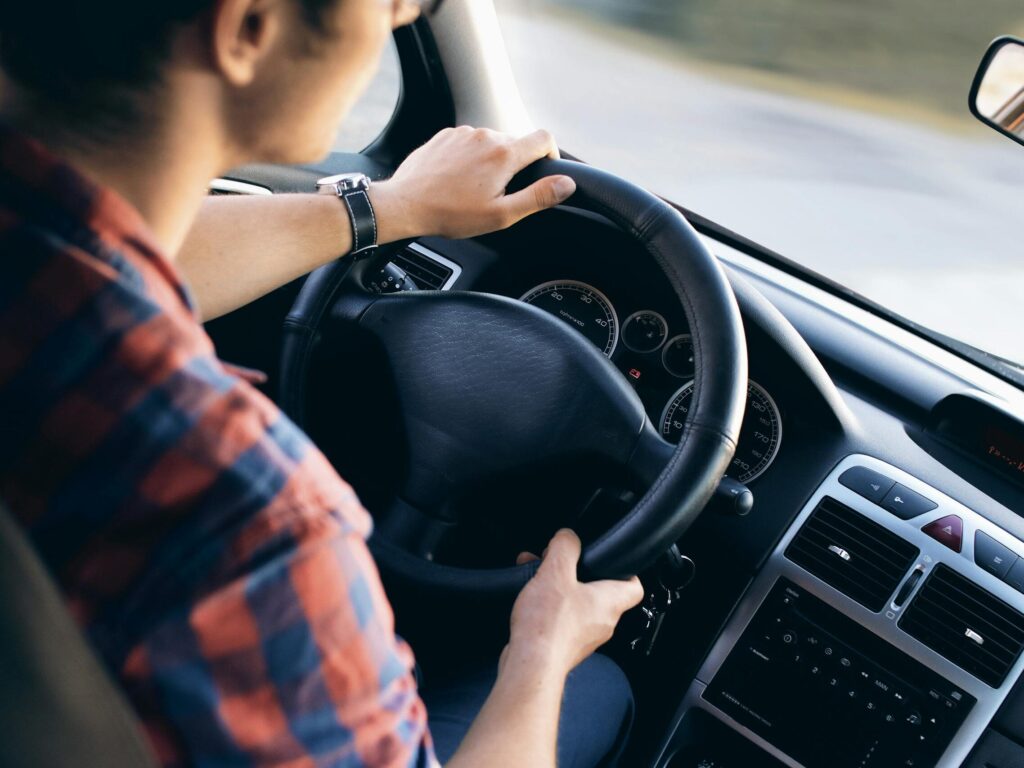 Close-up view of a man driving a modern car, showing dashboard and steering details.